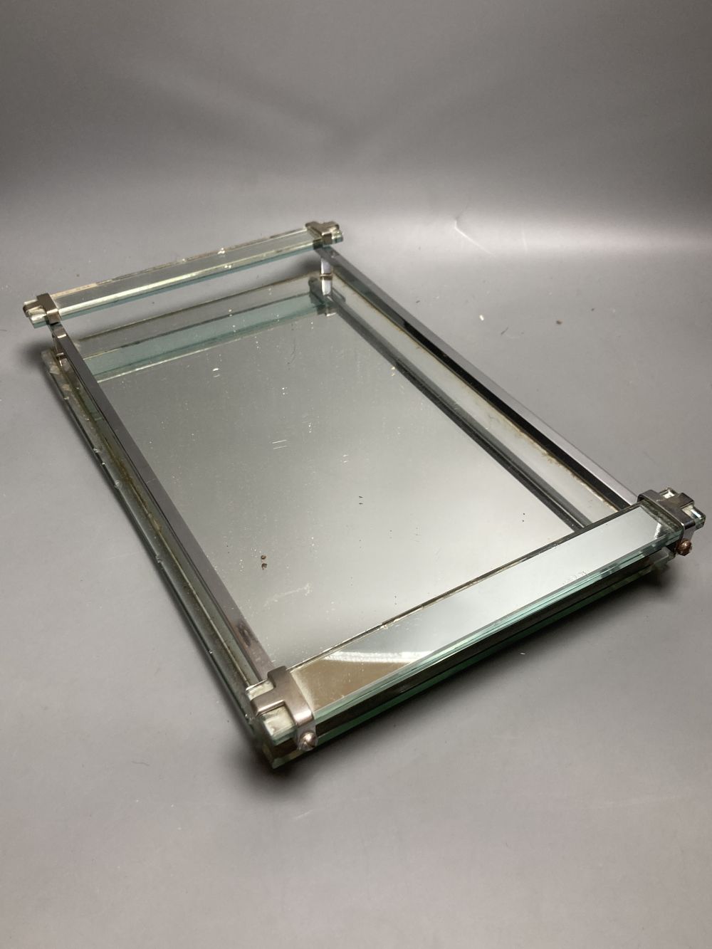 An Art Deco mirrored glass dressing table tray, 40 x 24cm and three Art Deco chrome plated dressing utensils